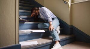 Injured person holding their knee after falling on stairs, illustrating slip and fall accident claims at Welcome Law Firm: Bridgeport Personal Injury & Immigration Lawyer