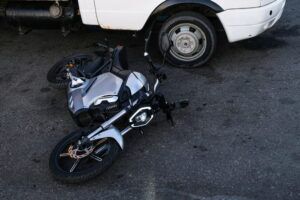 Motorcycle pinned beneath a vehicle after a collision, depicting motorcycle accident cases handled by Welcome Law Firm in Bridgeport